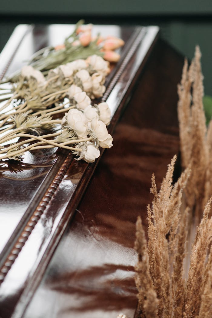 about-02 Close-up of a polished coffin adorned with delicate flowers, symbolizing loss and remembrance.