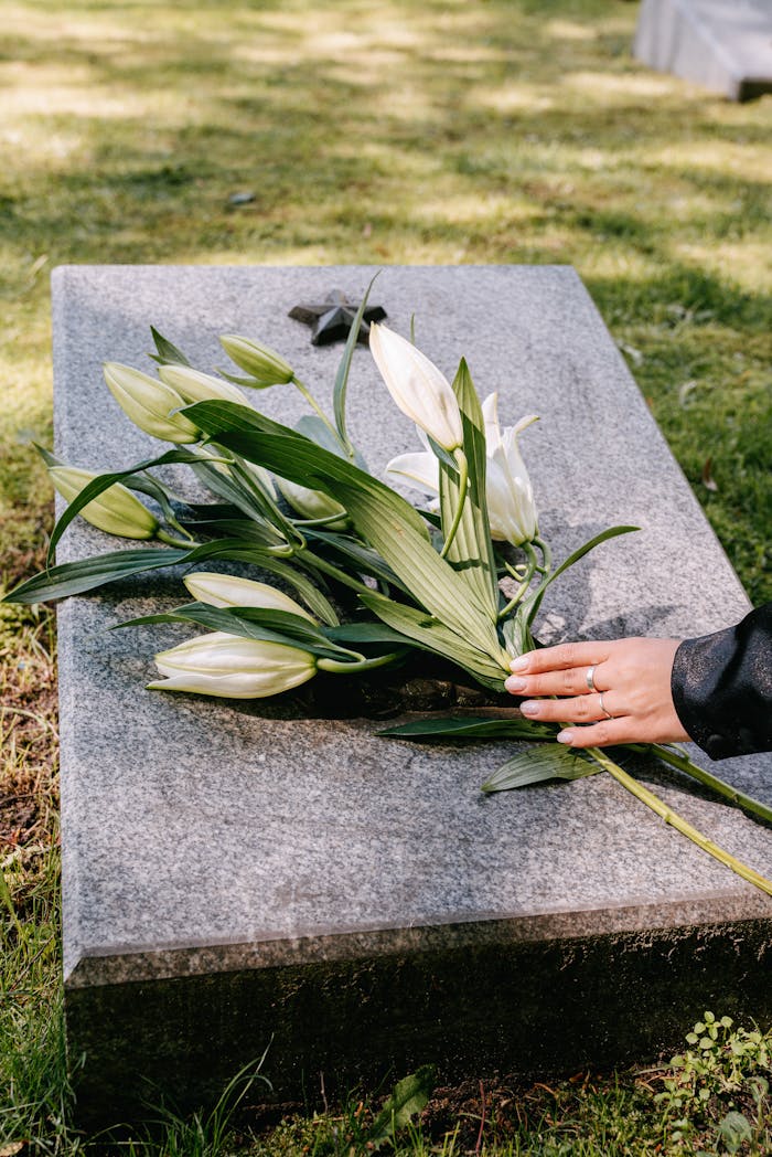 services-img White lilies on a gravestone symbolize remembrance in an outdoor cemetery setting.